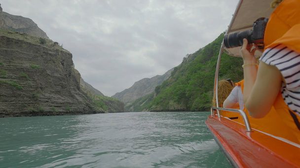 Excursión en barco por el río de montaña. Acción. Los turistas en chalecos nadan en barco en el río con vista a las rocas. Barco rafting en río turquesa con macizos rocosos en tiempo nublado - Foto, Imagen