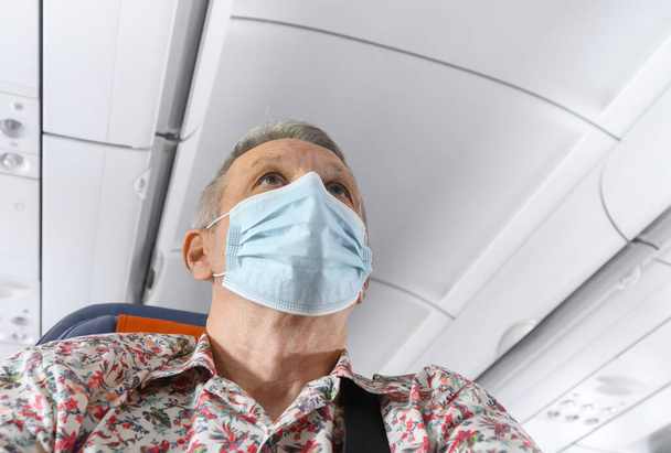 Man wearing mask in aircraft cabin. Prevention during Coronavirus pandemic - Zdjęcie, obraz