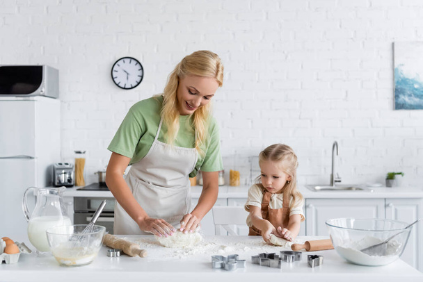 мать и дочь в фартуках смешивают тесто на кухне - Фото, изображение