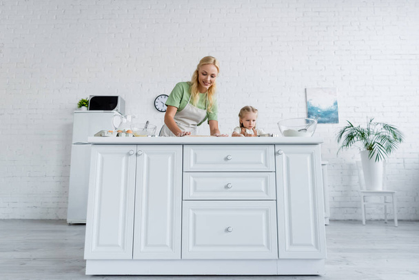 low angle view of mother and daughter cooking on white kitchen table - Fotografie, Obrázek