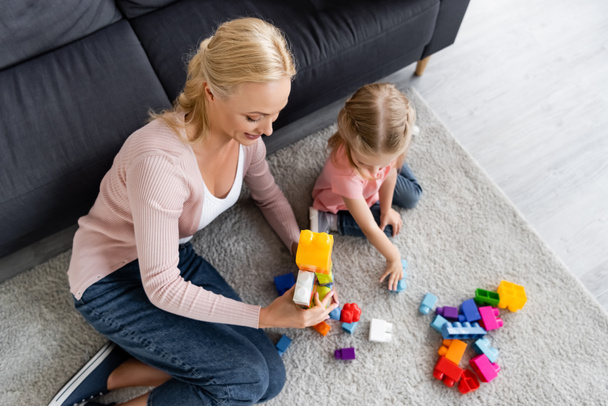 high angle view of child and mother playing with building blocks on floor  - Foto, afbeelding