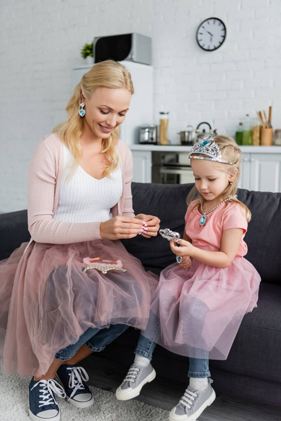 mother and child in fairy costumes playing on sofa at home - Photo, Image