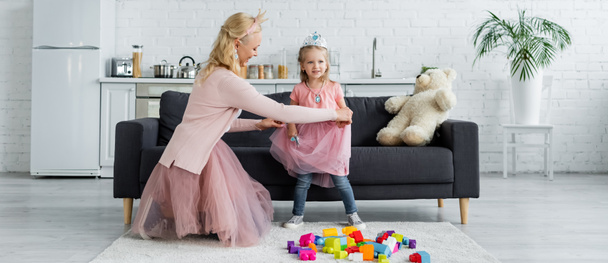 mom and kid in fairy costumes playing near building blocks on floor, banner - Photo, Image