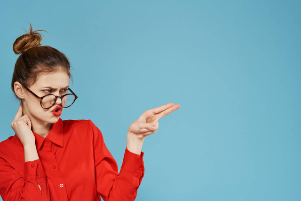 Business woman in red shirt wearing glasses showing something blue background. High quality photo - 写真・画像