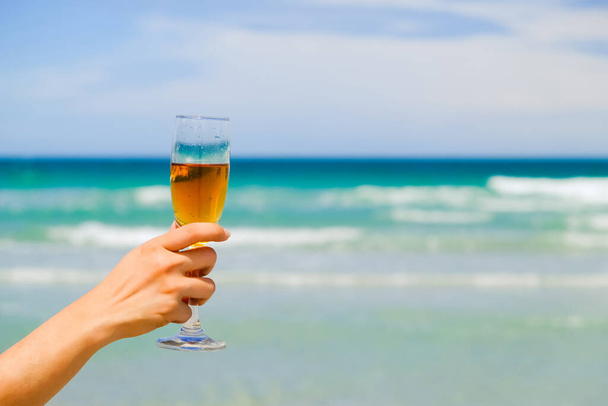 hands of female holding glasses of champagne on tropical sea beach - Фото, изображение