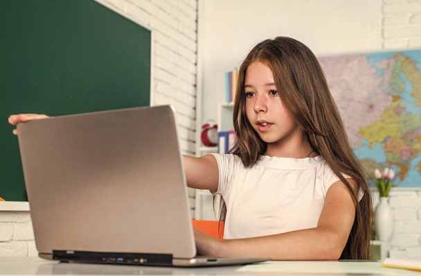 fröhliches Kind Mädchen mit Computer in der Schulstunde, e lernen - Foto, Bild