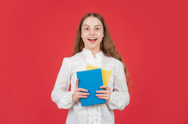 amazed child in white shirt ready to study do homework with book on red background, back to school - 写真・画像