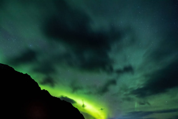 Silhueta de uma montanha na Islândia contra um céu claro com muitas estrelas e a Aurora Borealis, Luzes do Norte. Um efeito causado pela interação de partículas carregadas do sol com átomos na atmosfera superior. Islândia no inverno - Foto, Imagem