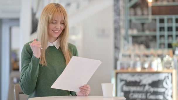 Woman Celebrating Success while Reading Documents in Cafe  - Фото, зображення