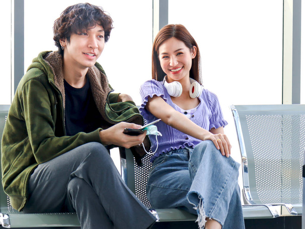 Asijské mladý cestovatel milenec pár sedí na terminálu židle sedadlo se zavazadlovým kufrem, s konverzací, se smíchem a baví spolu, šťastný přítel cestování na dovolenou.  - Fotografie, Obrázek