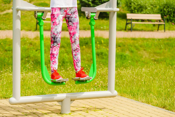 Woman training on sport machine in city park. Female legs exercises on street simulator. Sports equipment in public place. - Foto, Bild