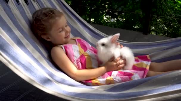 Šťastná holčička s pozitivními emocemi bledne se svým mazlíčkem, bílým králíčkem.  - Záběry, video