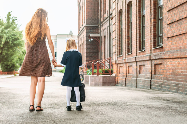First day at school. Mother leads a little child school girl in first grade - Фото, зображення