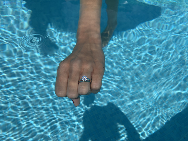 Yüzme havuzunda elmas bir yüzükle zarif bir kadın eli.. - Fotoğraf, Görsel