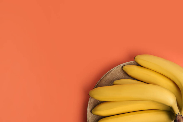 Ripe yellow bananas on coral background, top view. Space for text - Photo, image
