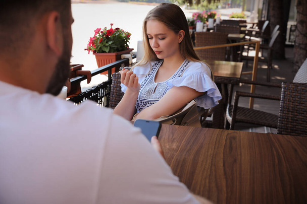 Young woman having boring date with guy in outdoor cafe - 写真・画像