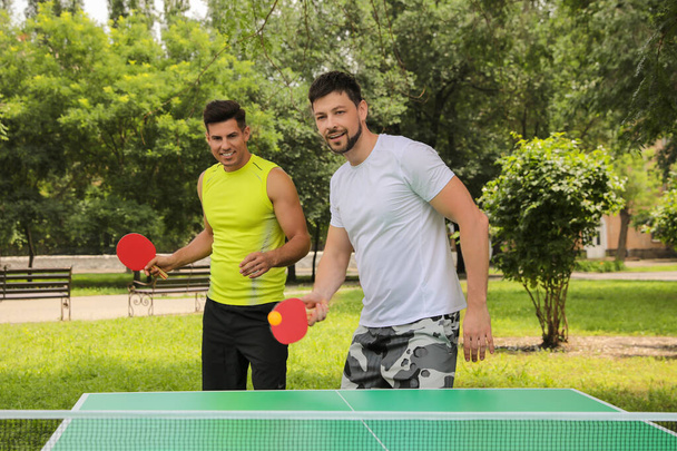 Männer spielen an Sommertagen Tischtennis im Park - Foto, Bild