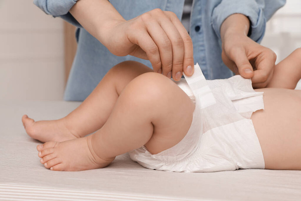 Mother changing baby's diaper on bed at home, closeup - Photo, Image