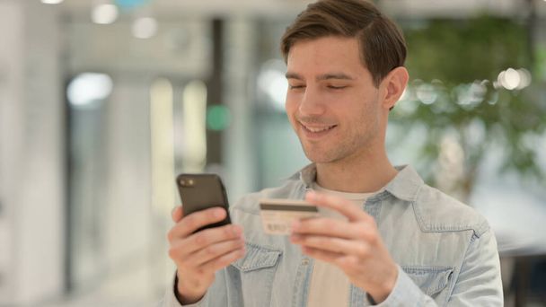 Jonge man winkelen Online op Smartphone - Foto, afbeelding