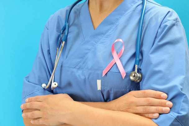 Verpleegster met borstkanker bewustmakingslint, close up - Foto, afbeelding