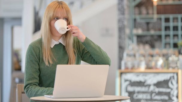Γυναίκα πίνοντας καφέ, ενώ εργάζονται σε Laptop στο Cafe  - Φωτογραφία, εικόνα