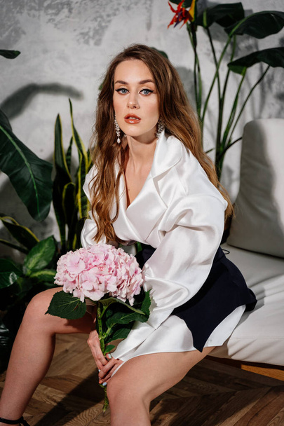 hermosa joven con el pelo largo en un vestido blanco y un ramo de flores - Foto, Imagen