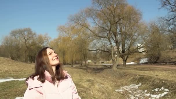 Una ragazza in giacca rosa lancia una palla di fili in un parco primaverile autunnale al rallentatore - Filmati, video