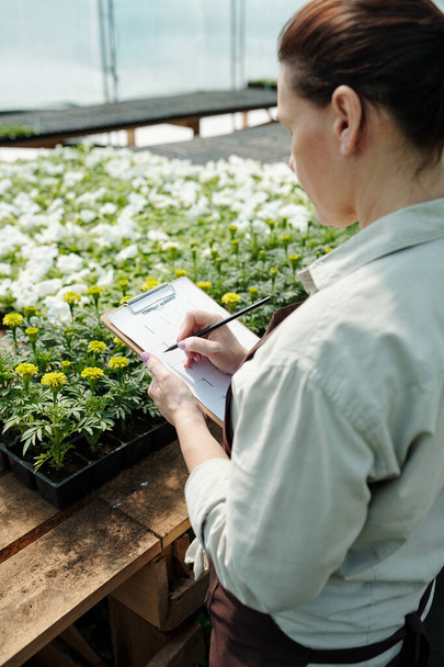 Współczesny rolnik robi notatki na papierze stojąc w miejscu pracy - Zdjęcie, obraz