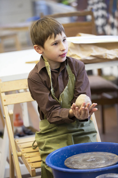 Um menino faz um produto de barro na roda de um oleiro. - Foto, Imagem