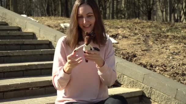Une belle fille dans un chemisier rose joue avec un cheval jouet tricoté et raconte le processus de crochet et amusez-vous et souriant - Séquence, vidéo