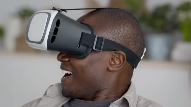 Emocionado hombre negro con gafas VR experimentando realidad virtual en interiores - Imágenes, Vídeo