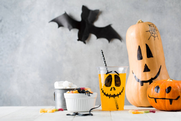 Drinks sweets and pumpkins with frightful faces on table - Photo, Image