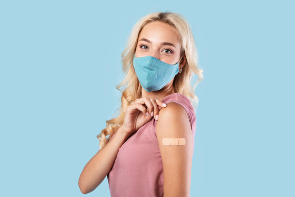 Happy Vaccinated Woman In Mask Showing Adhesive Bandage After Vaccine - Fotografie, Obrázek