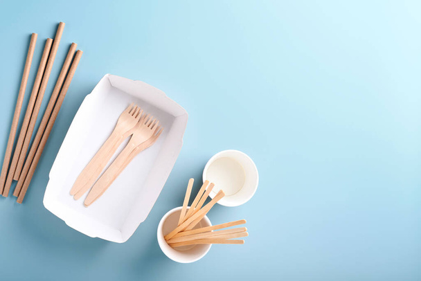 Paper cups, dishes, bag, wooden forks, drinking straws, fast food containers, wooden cutlery on light blue background. Eco craft paper tableware. Recycling and food delivery concept. Mock up. Top view - Photo, Image