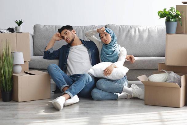 Εξαντλημένη αραβική οικογένεια που κάθεται στο πάτωμα ανάμεσα σε χάρτινα κουτιά - Φωτογραφία, εικόνα