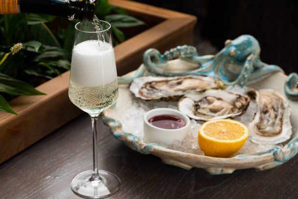 fresh open oysters with sauce, lemon and a glass of wine - Фото, зображення