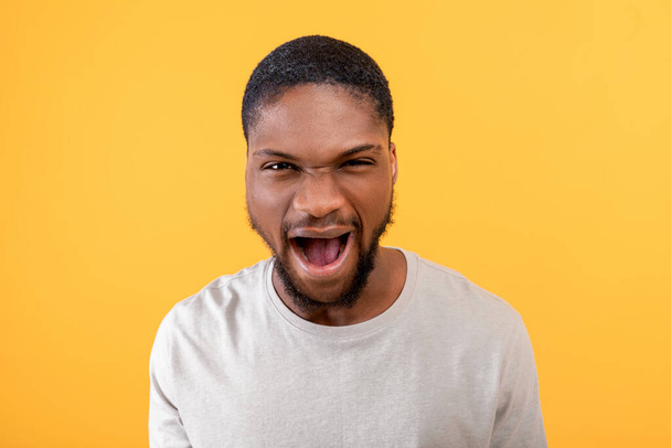 Fury. Angry black guy shouting emotionally at camera, expressing anger and aggression over yellow background - Photo, Image