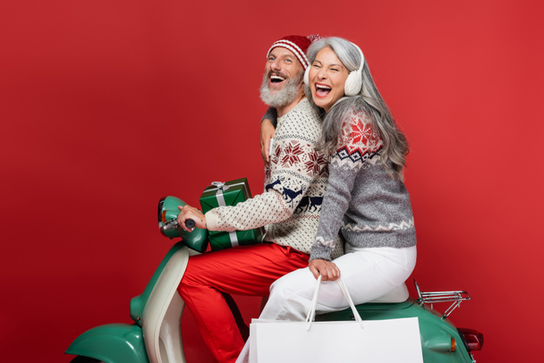 興奮して異人種間の成熟したカップルクリスマスプレゼントは赤い上に乗り降り - 写真・画像