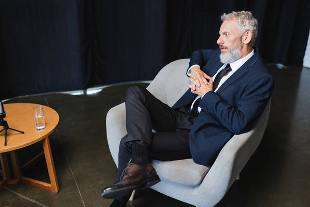 businessman in suit sitting on armchair during talk show  - Fotografie, Obrázek
