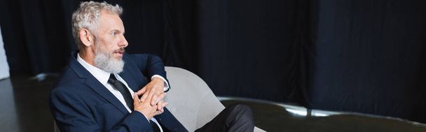 businessman in suit sitting on armchair during talk show, banner - Foto, imagen