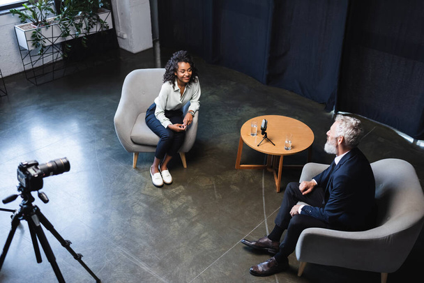 vysoký úhel pohledu šťastný africký americký novinář mluví s hostem v rozhovoru studio  - Fotografie, Obrázek