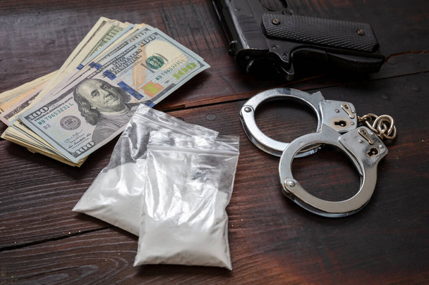 Cocaine plastic packets, pistol US dollars banknotes and handcuffs. Drugs narcotics possesion and use, arrest and punishment for illegal business concept.  - Photo, Image