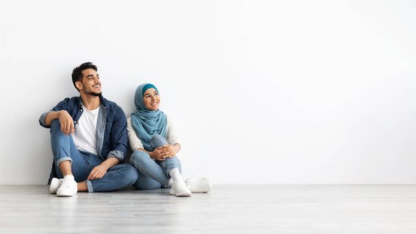 Wesoła kobieta w hidżabie siedzi na podłodze ze swoim mężem - Zdjęcie, obraz