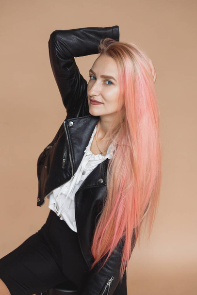 Красивая блондинка в черной кожаной куртке и розовые волосы в стиле рок на обычном фоне - Фото, изображение