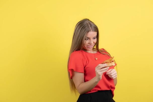 Image of alluring woman holding a piece of delicious pizza . High quality photo - Foto, afbeelding