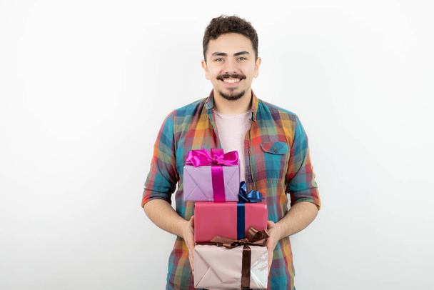 Porträt eines attraktiven Mannes, der Geschenkkartons in der Hand hält und in die Kamera blickt. Hochwertiges Foto - Foto, Bild