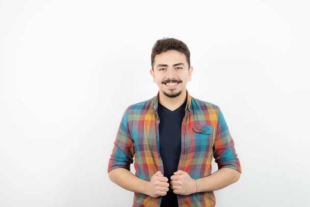 Obrázek mladého pohledného muže oblečeného v kostkovaném tričku a stojícího nad bílou zdí. Kvalitní fotografie - Fotografie, Obrázek