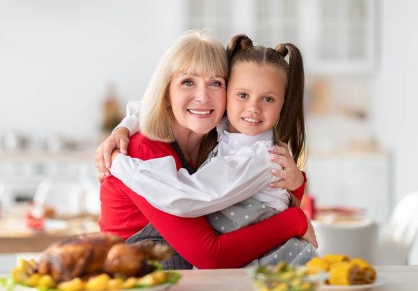 Mulher idosa abraçando sua neta enquanto cozinha jantar festivo em família com peru gostoso em casa - Foto, Imagem