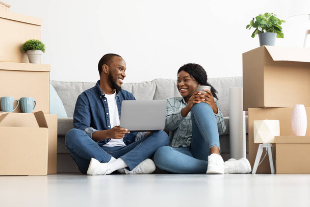 Áthelyezési koncepció. Boldog fekete házastársak Laptop használata az új lakásban - Fotó, kép