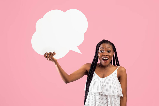 Shocked Afro woman holding blank speech bubble with mockup for ad design on pink studio background - Photo, Image